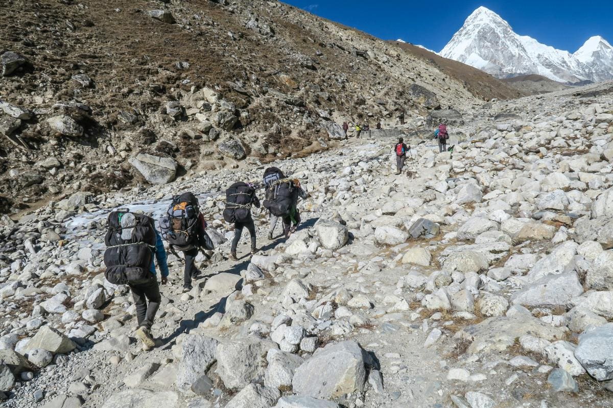 People walking with backpacks during an adventure to climb Mount Everest