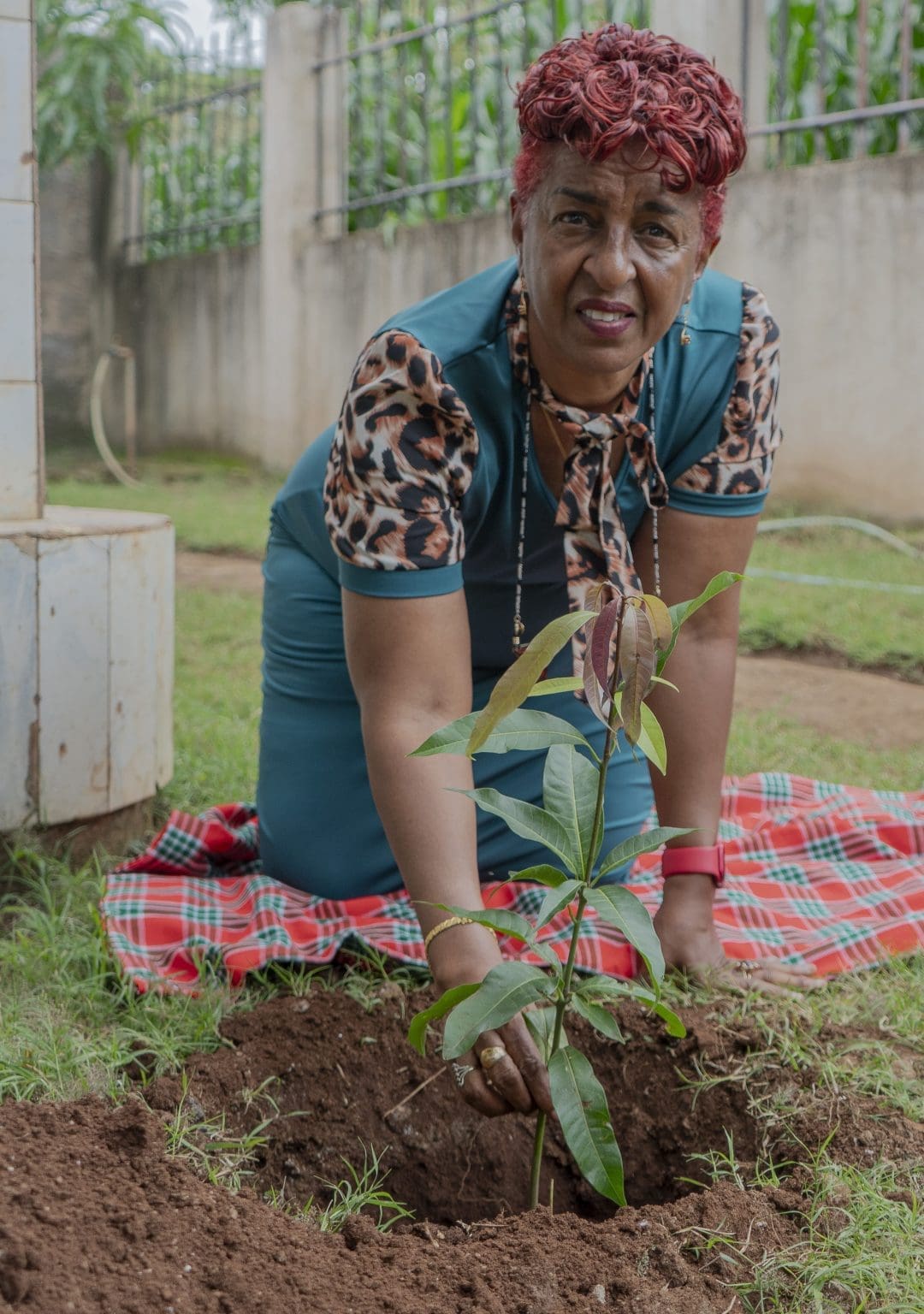 Mama Zara planting a young tree as part of a community environmental initiative.