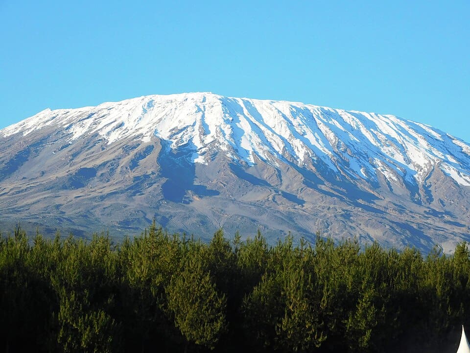 Mount Kilimanjaro with ice-covered summit visible above clouds.