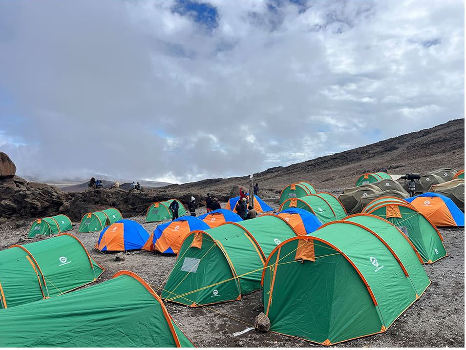 Colourful tents set up at Kibo Camp on the Rongai Route of Mount Kilimanjaro, with trekkers preparing for the summit push.