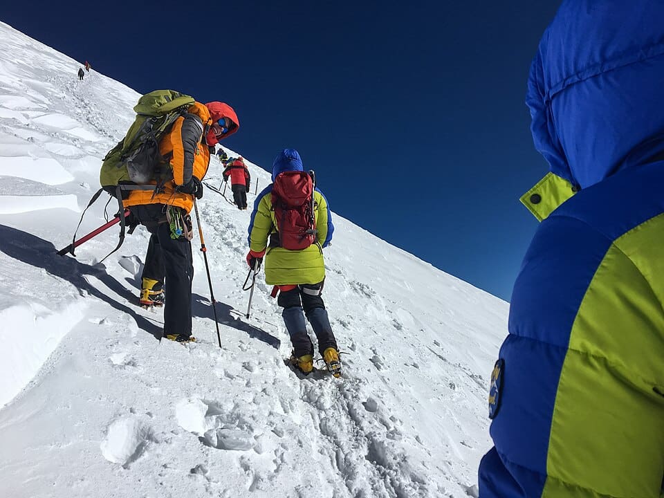 Climbers ascending the west peak of Mount Elbrus on a clear morning.