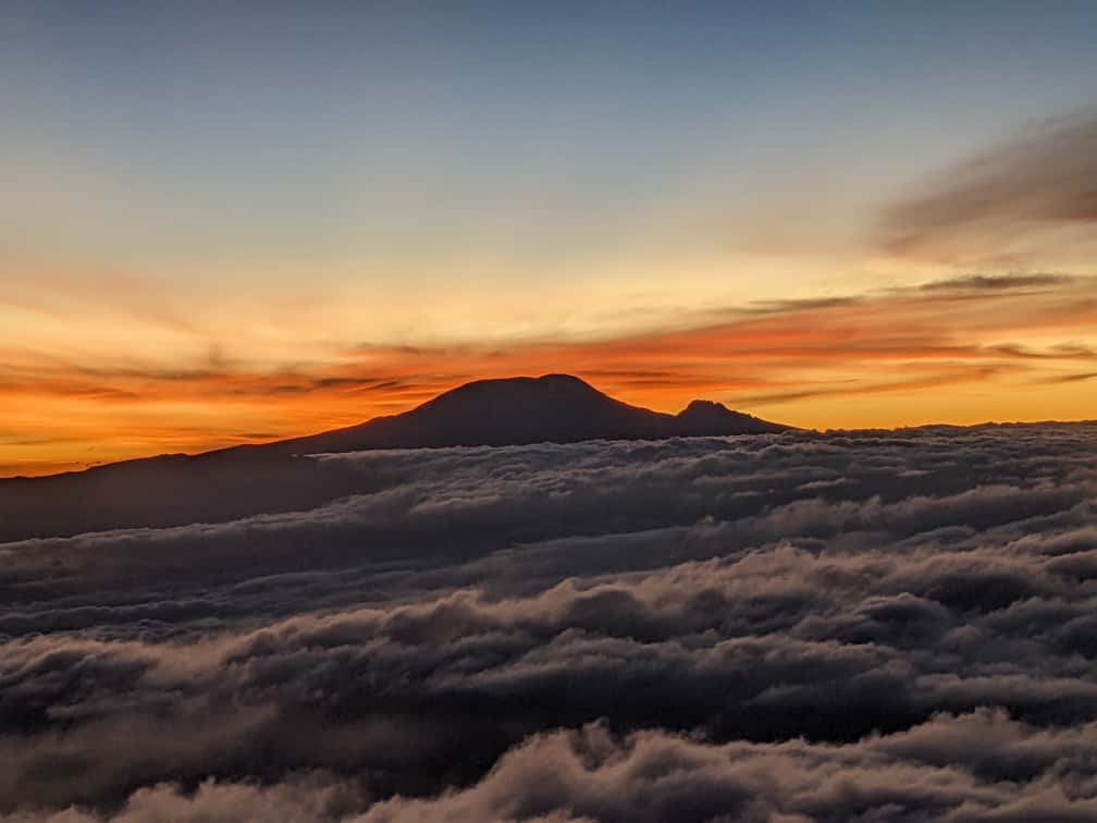 Sunrise over Mount Kilimanjaro with the peak rising above a sea of clouds.