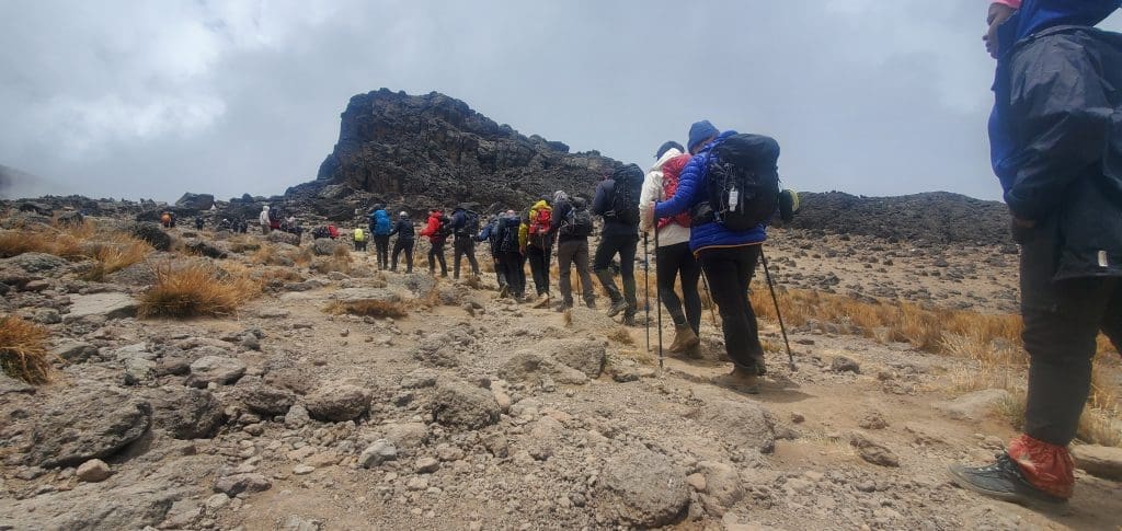 Climbers hiking uphill on rocky terrain.
