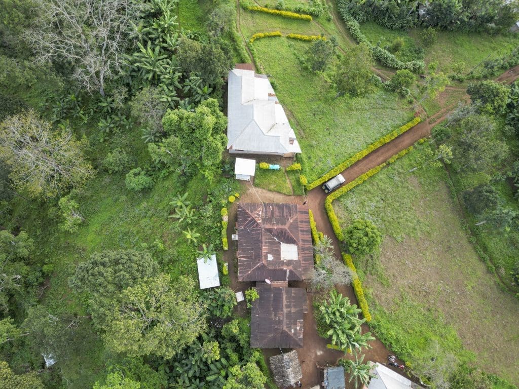 Aerial view of Materuni Village on the lower slopes of Mount Kilimanjaro, showing farms, homes, and lush cultivated land.