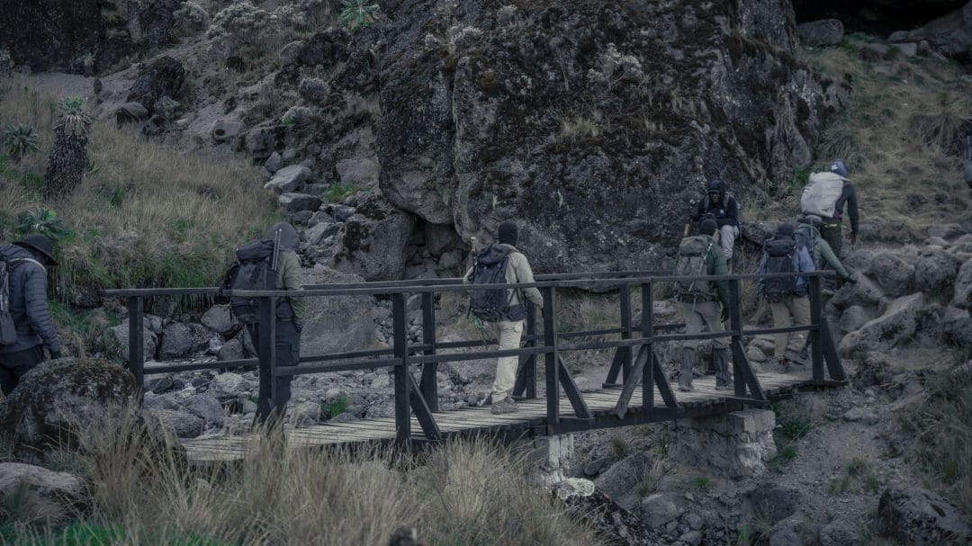 Climbers crossing a wooden bridge on Mount Kilimanjaro during a guided trekking expedition